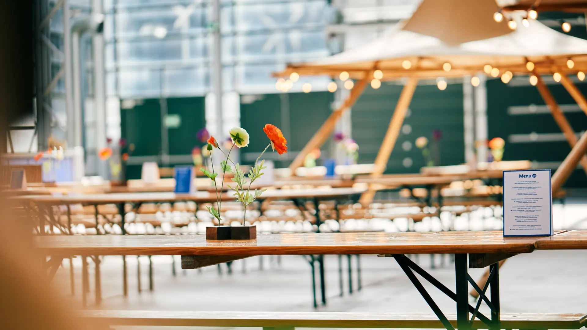 Længere borde og blomsterdekorerede spisepladser klar til sommerfest i Bella Center.