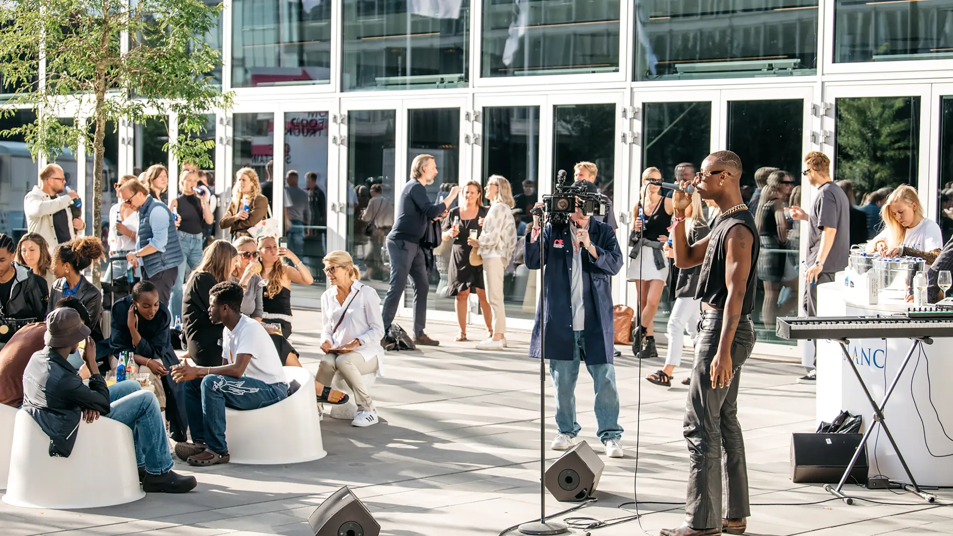 Udendørs event med liveoptræden, publikum og kamerahold foran Bella Center.