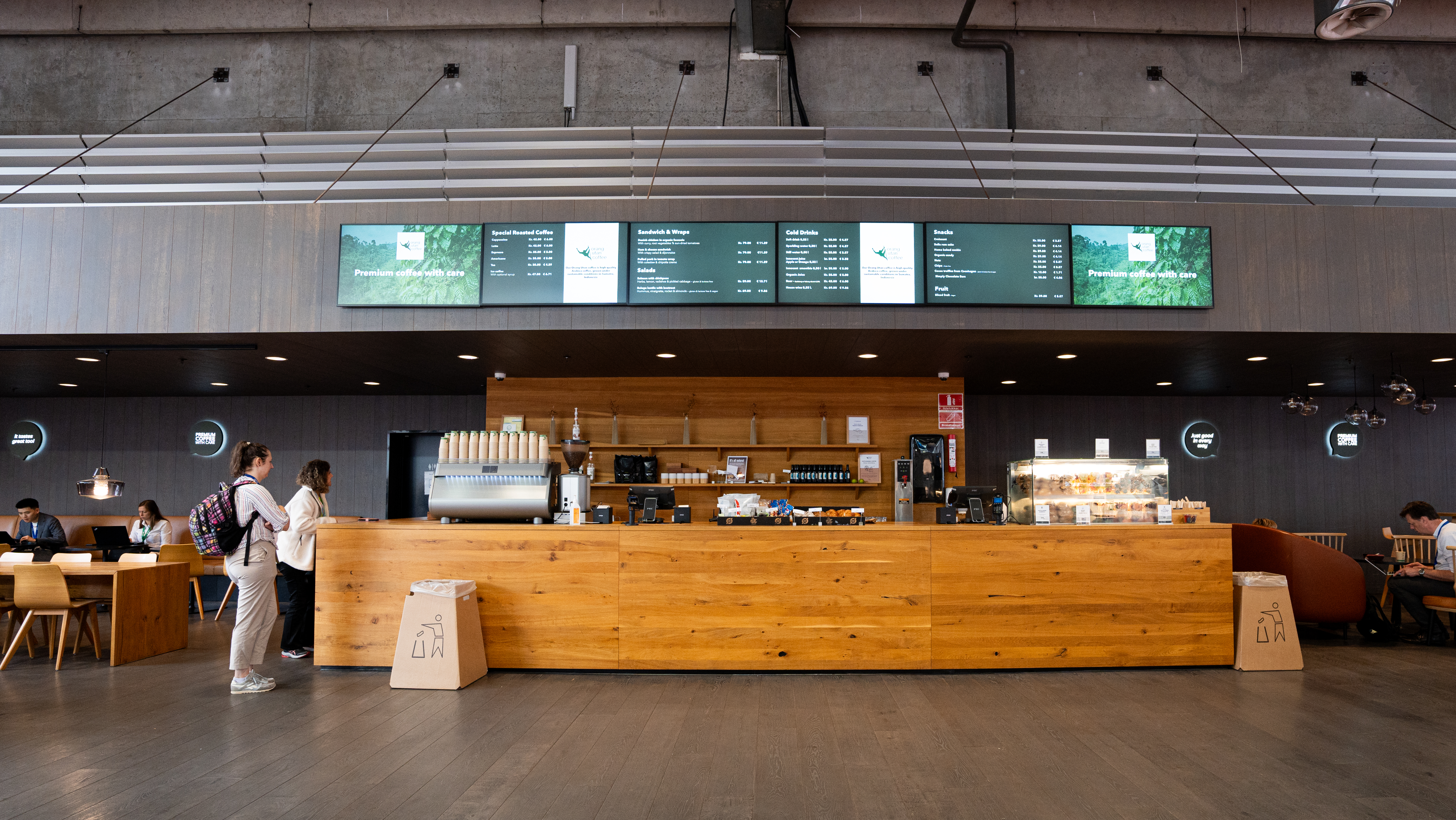 Premium Coffee i Bella Center – kaffebar med træfront, sort vægbeklædning og digitale menutavler.