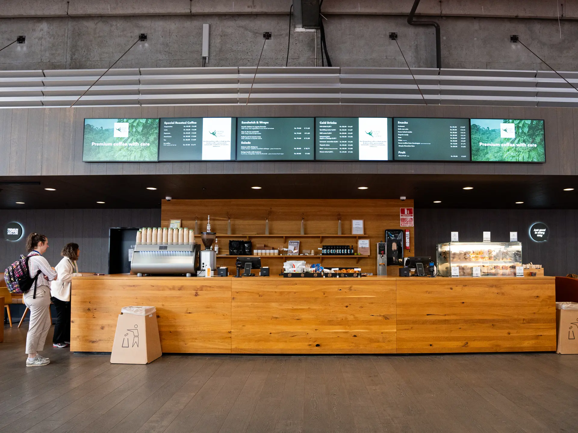 Premium Coffee i Bella Center – kaffebar med træfront, sort vægbeklædning og digitale menutavler.