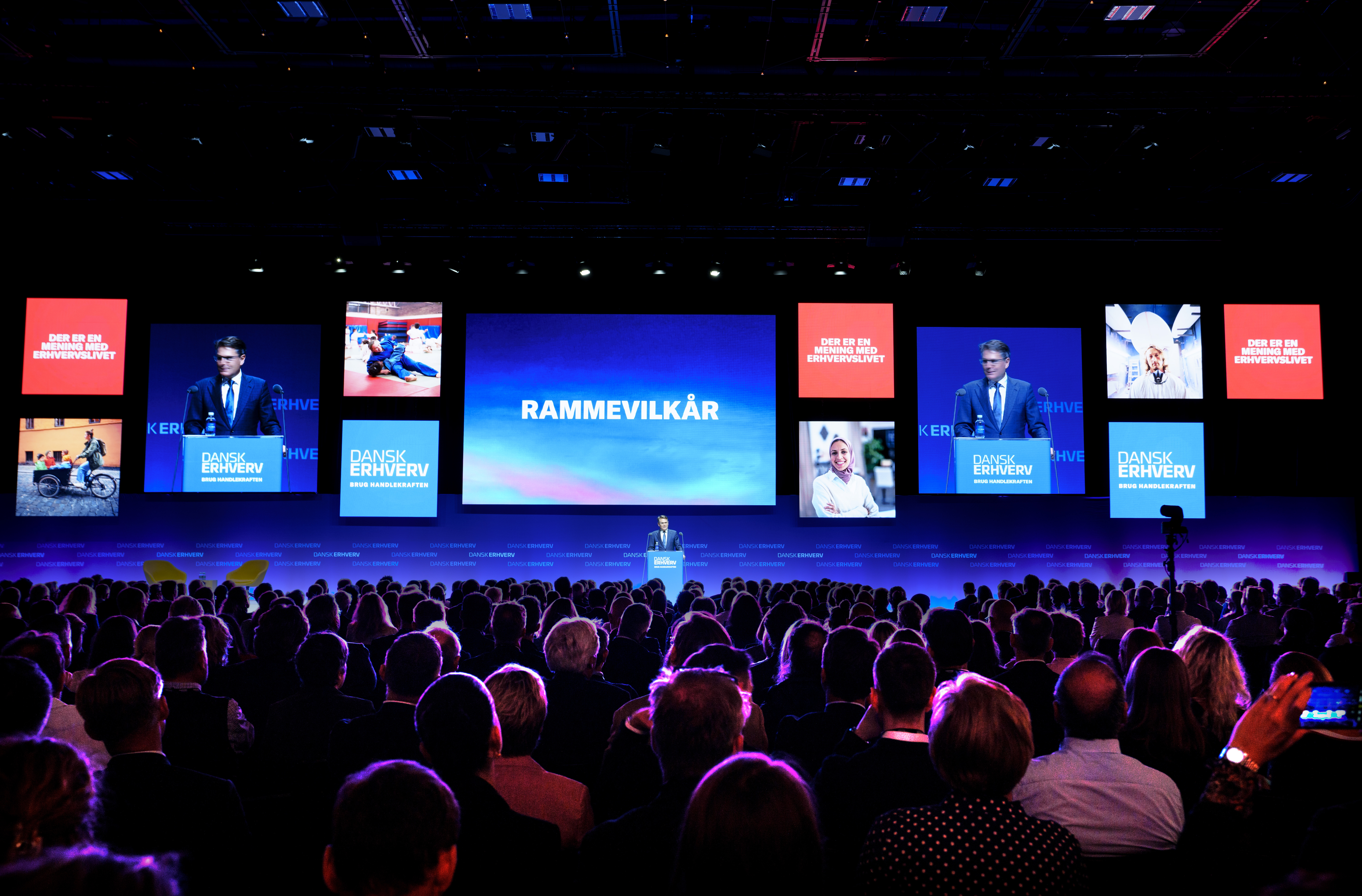 Fuld sal under konference i Bella Center med store skærme og blå belysning.