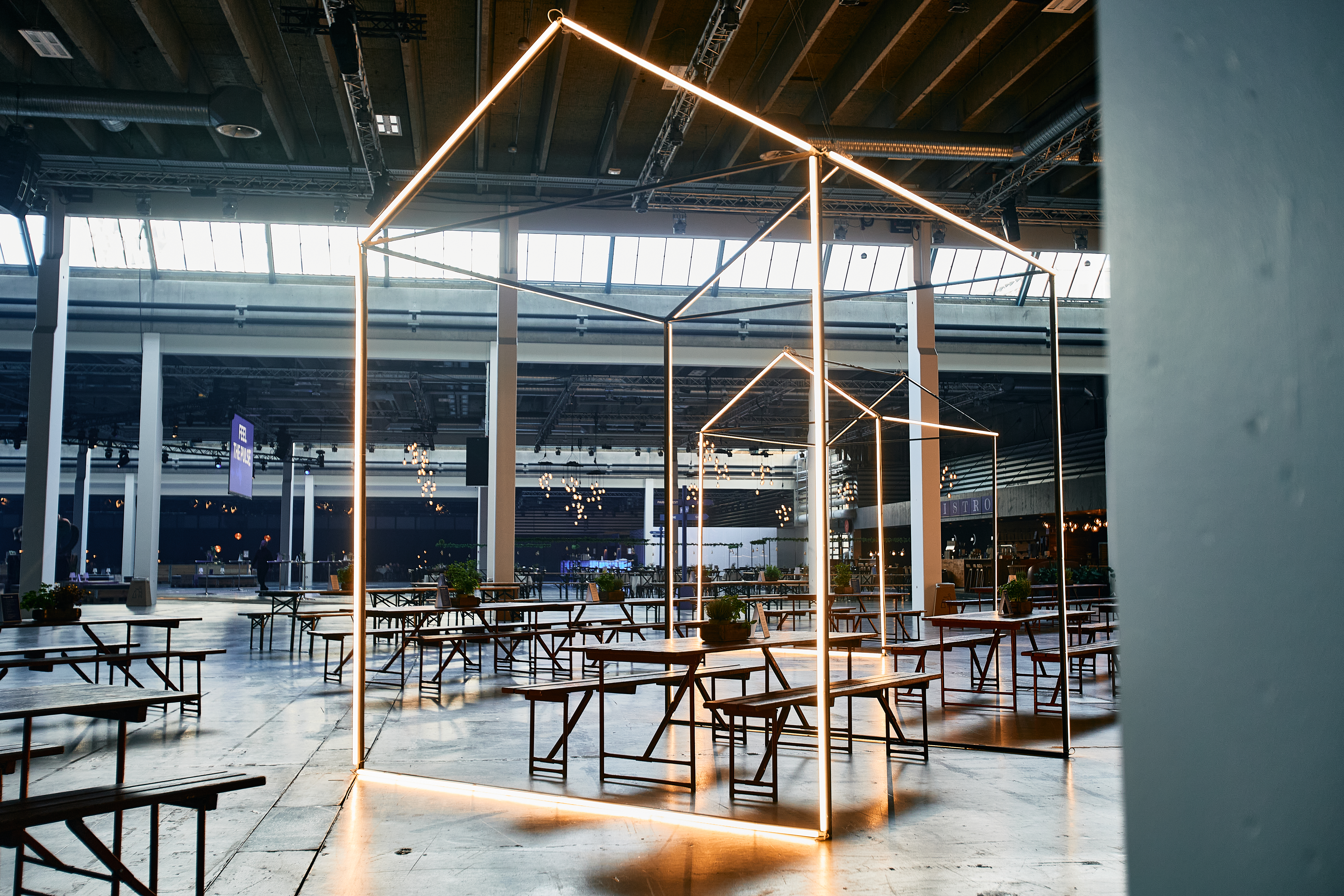 Spiseområde med langborde og lysinstallationer.