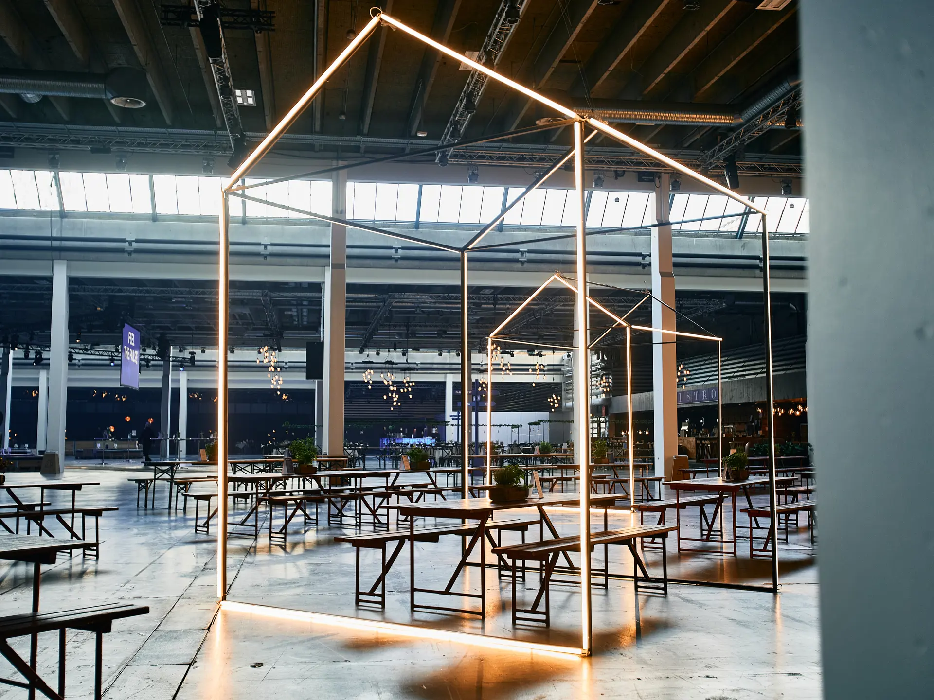 Spiseområde med langborde og lysinstallationer.