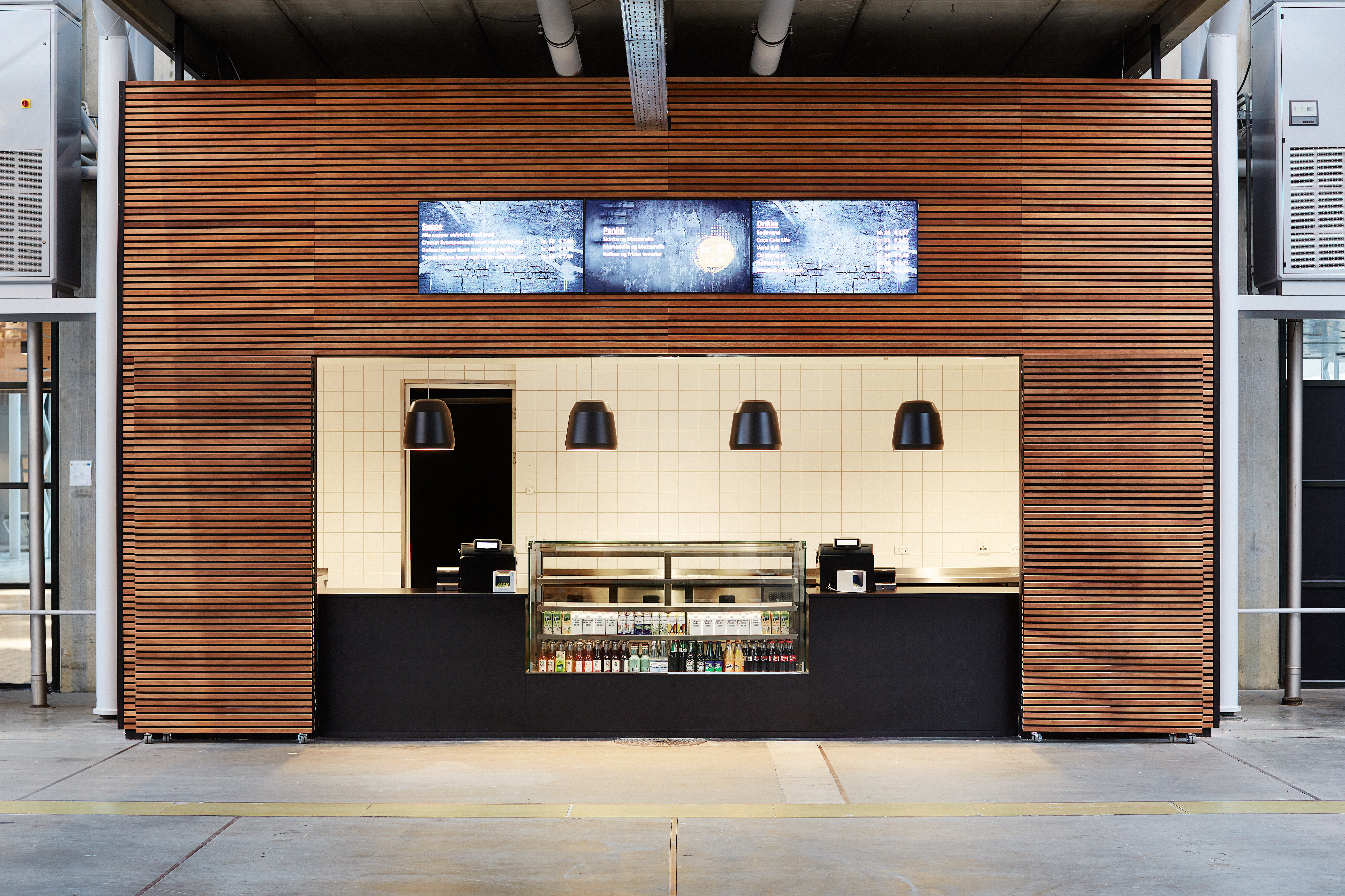 Food Grab – sort og træbeklædt takeaway-område med moderne belysning og kølediske med drikkevarer.