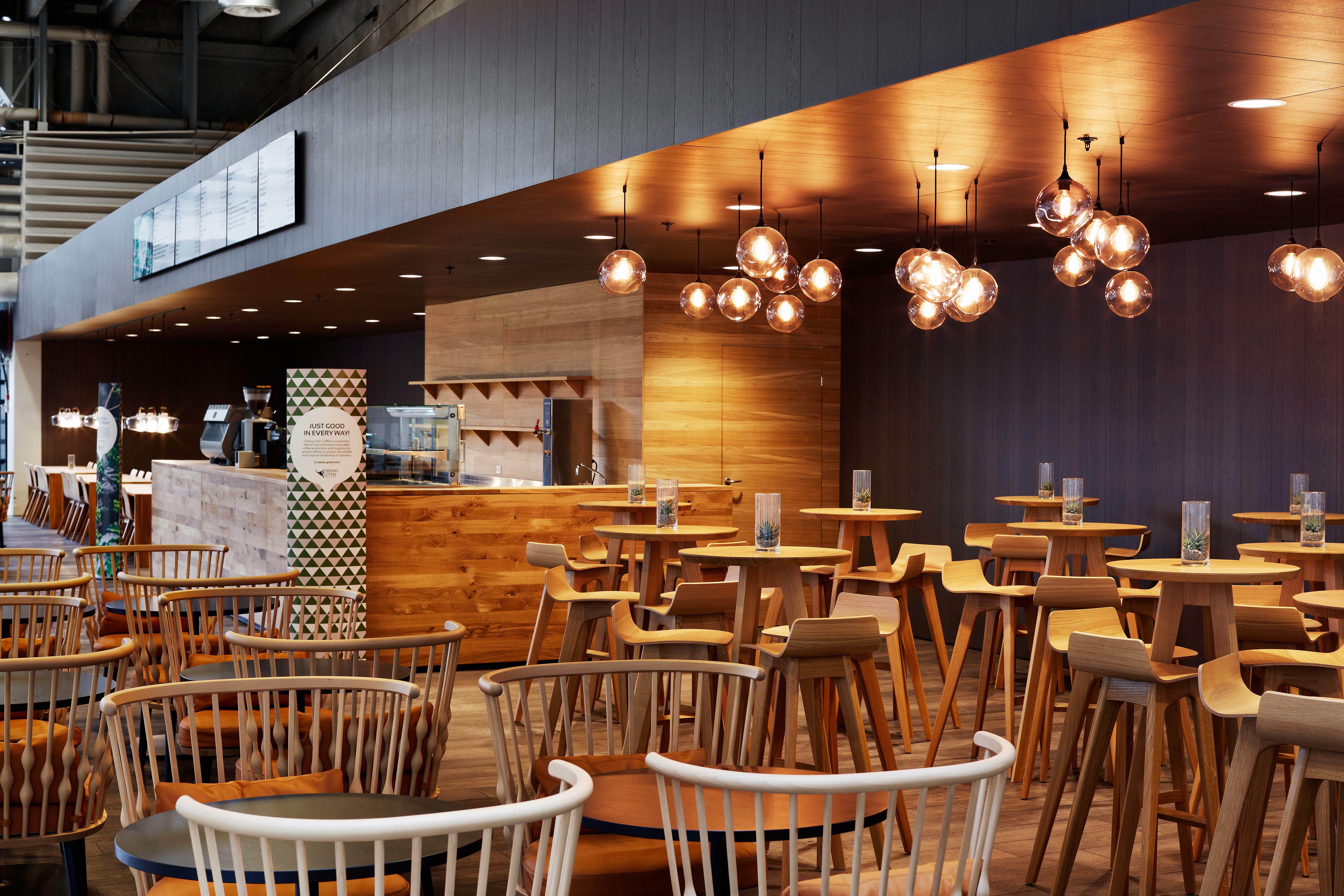 Orangu Lounge – caféområde med højborde, barstole og dekorative loftslamper i klynger.