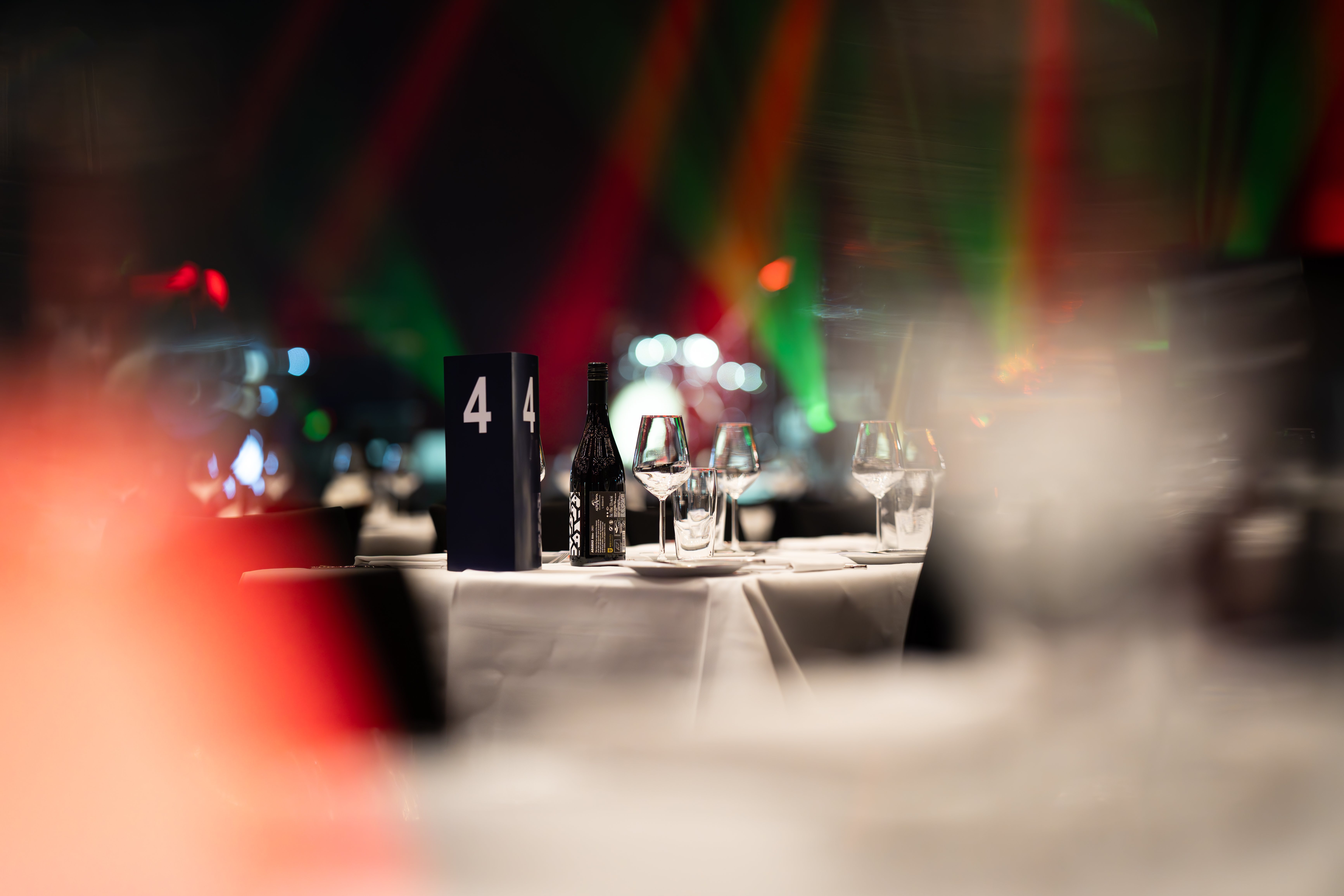 Nærbillede af opdækket bord med vinflaske, glas og nummer til julefrokost i Bella Center.