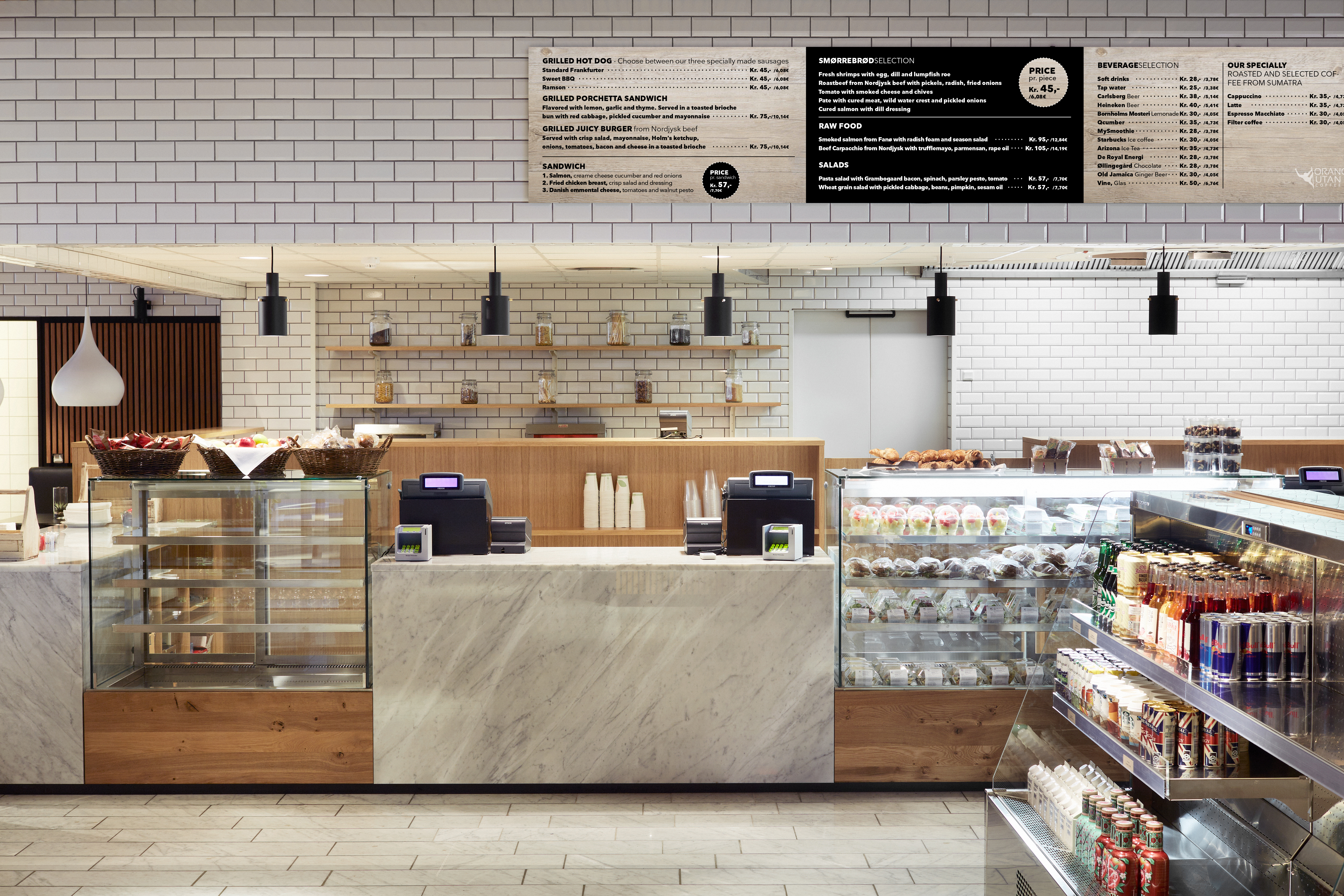 The Gastro – frontdisk med marmordetaljer, glasmontrer fyldt med friskbagte brød, sandwiches og kolde drikke.