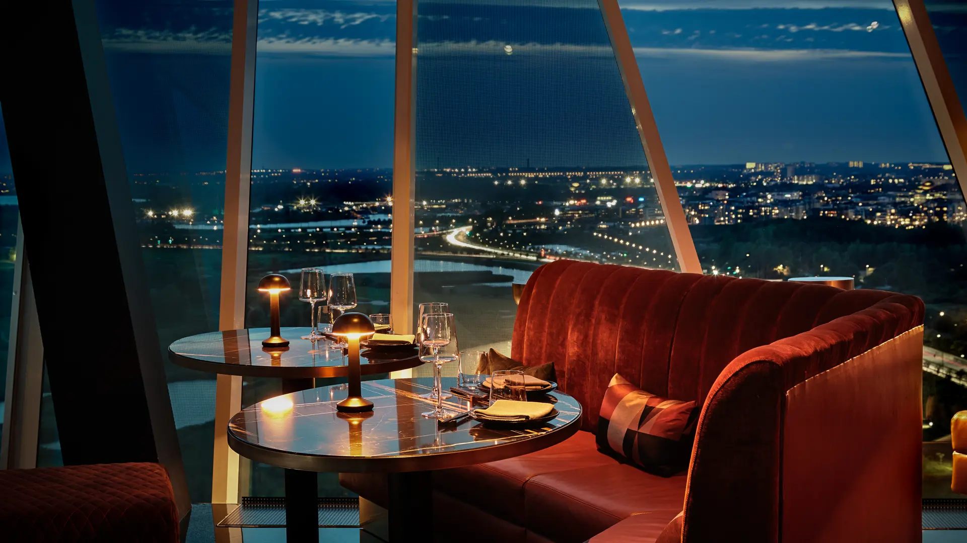 Eksklusiv restaurant med panoramaudsigt over København fra Bella Center, med elegant borddækning og stemningsfuld aftenbelysning.