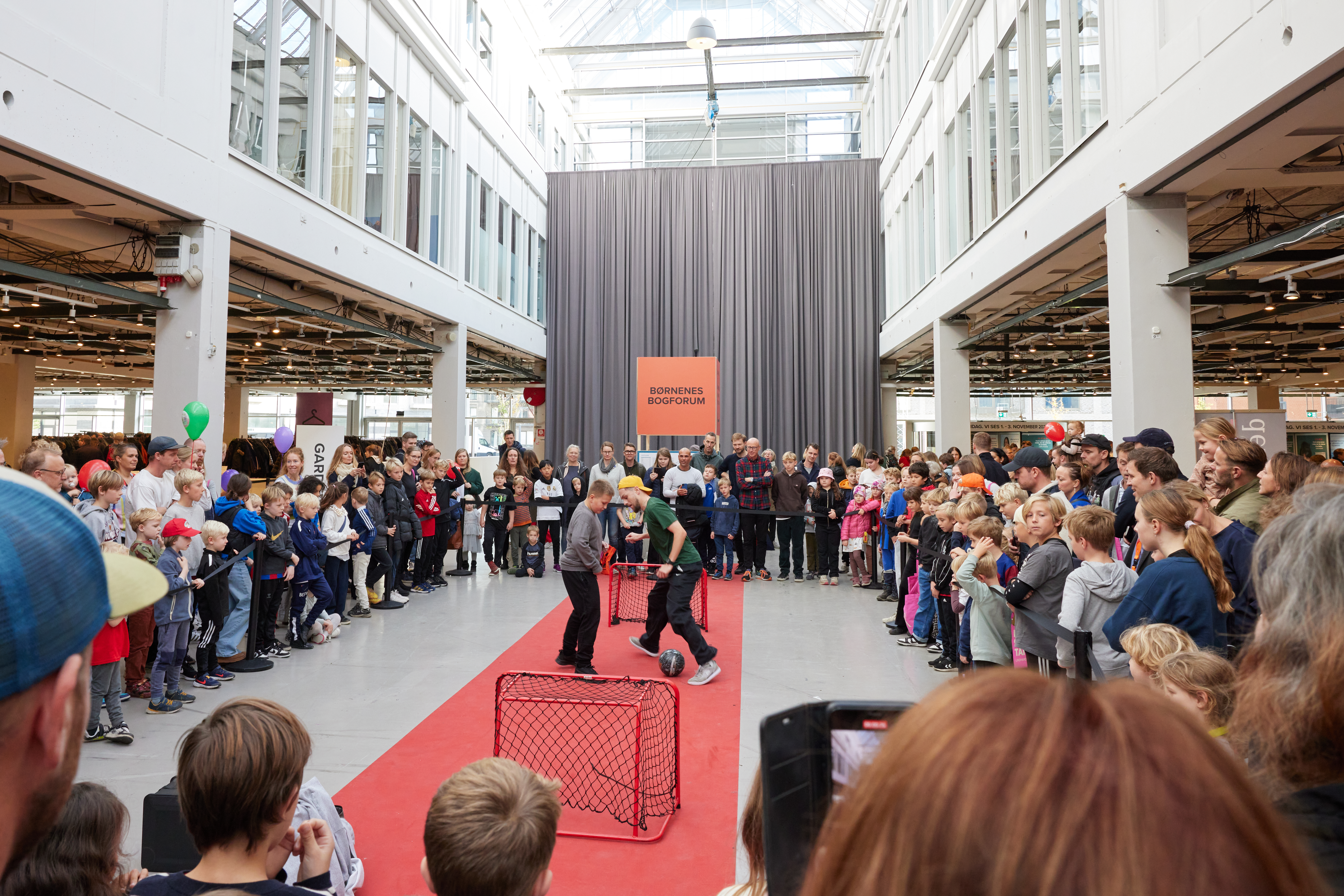 To børn spiller fodbold foran publikum til Bogforum i Bella Center Copenhagen.