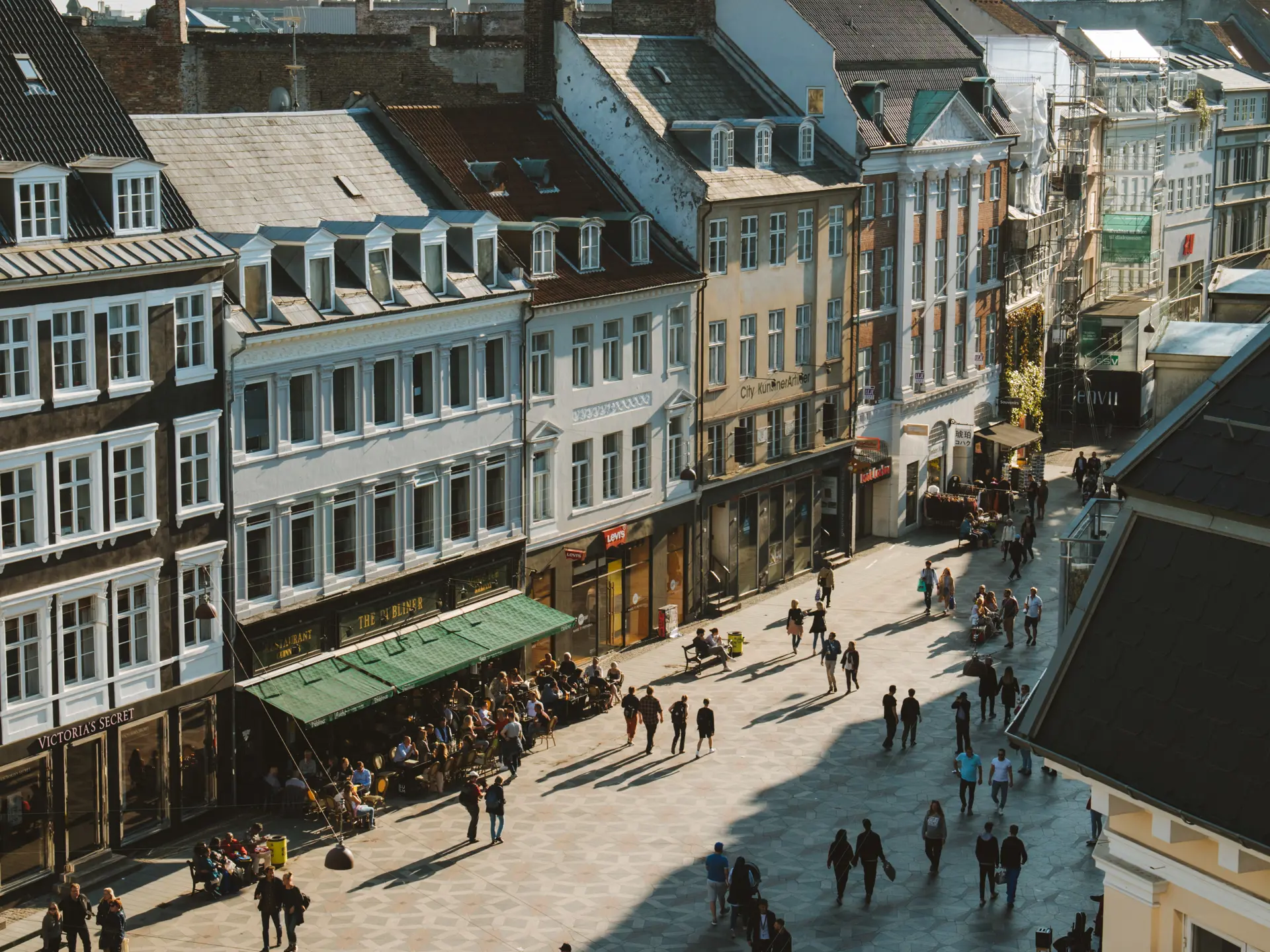 Folk på shoppinggade i København med historiske facader