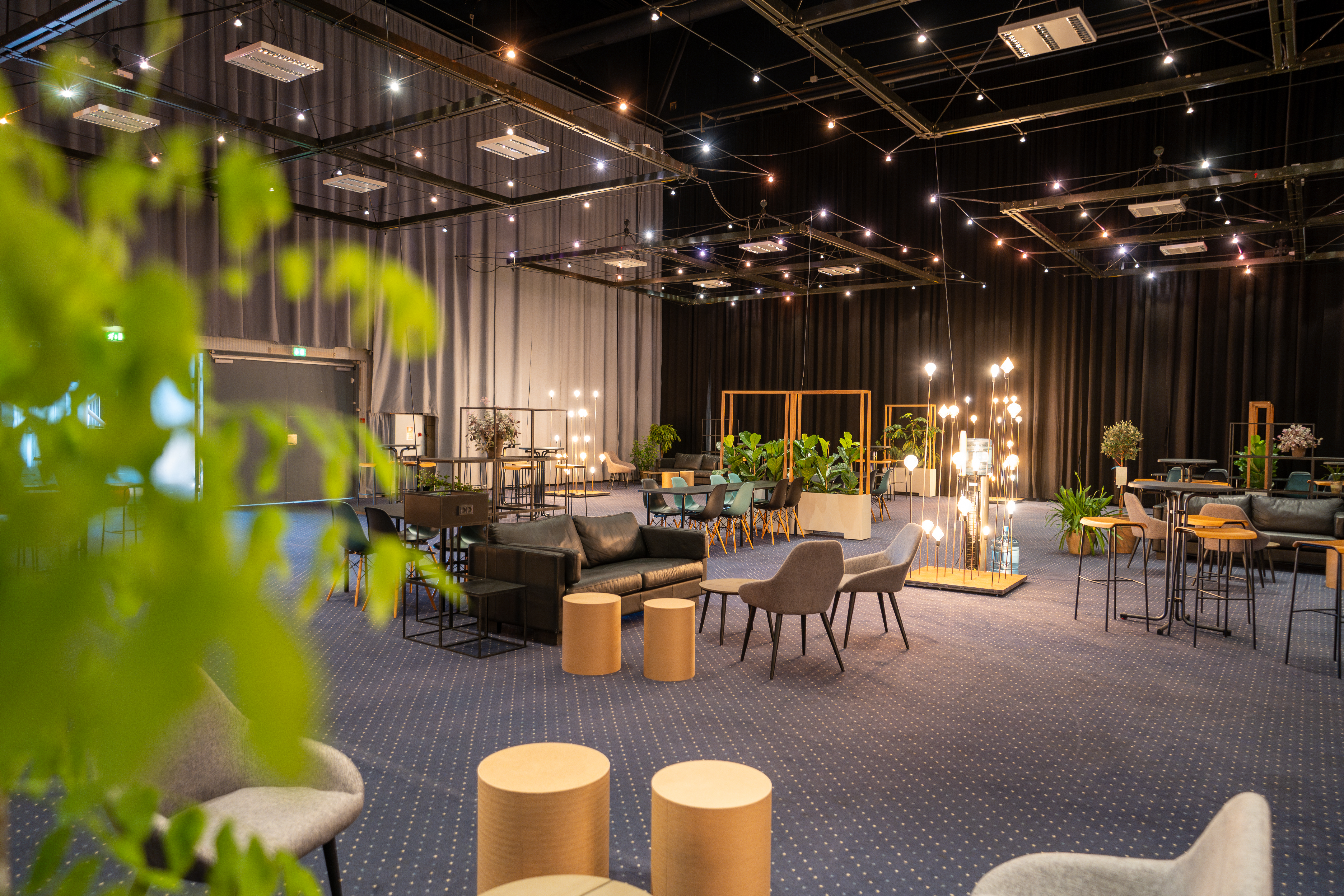 Loungeområde i Hal A med sofaer, grønne planter og belysning.