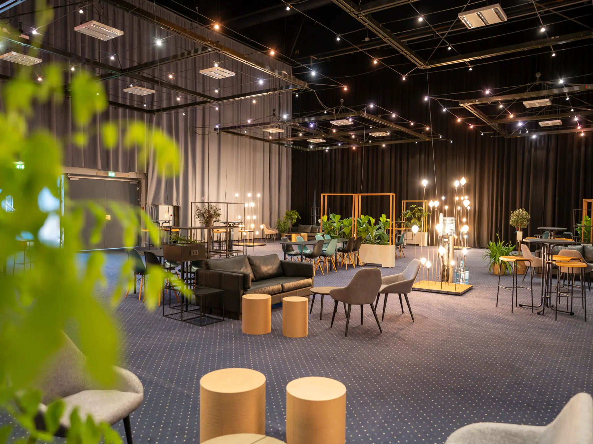 Loungeområde i Hal A med sofaer, grønne planter og belysning.