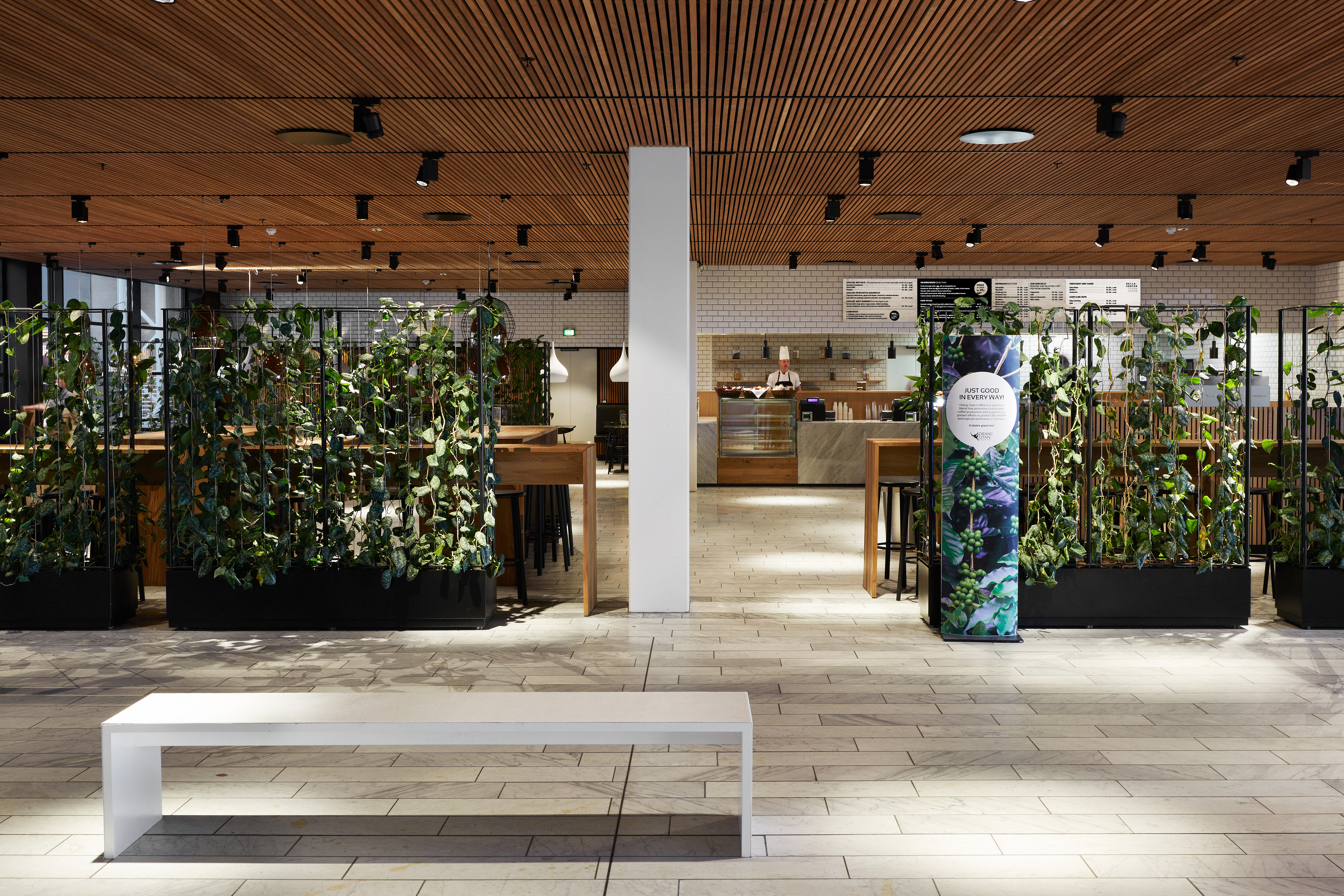  The Gastro – indgangsområde med grøn plantevæg, hvide klinker og udsigt til caféområdet.