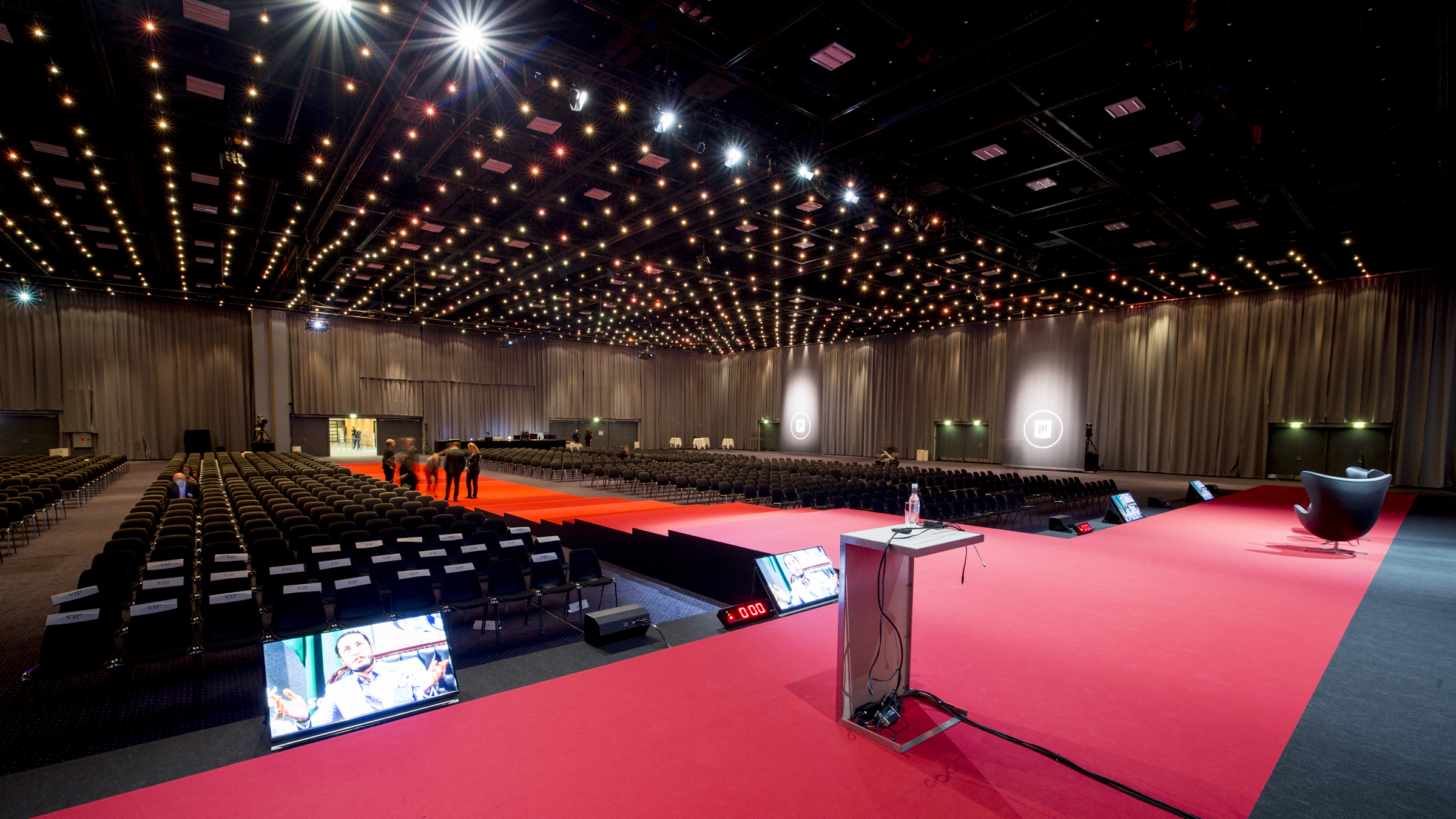 Hal A i Bella Center med scene, storskærme og stoleopstilling til konference eller kongres.