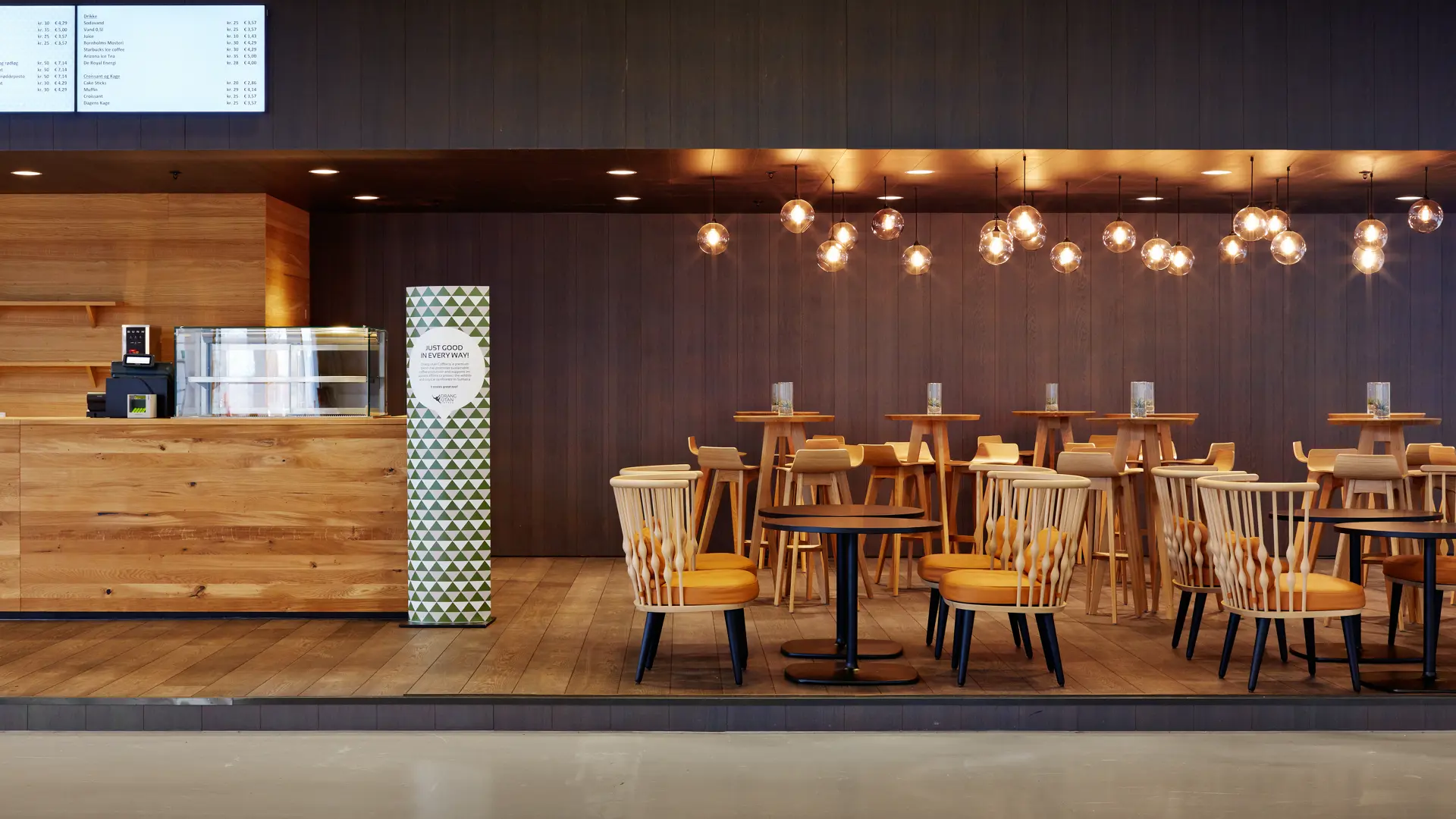 Orangu Lounge i Bella Center – varm lounge med træmøbler, lyse lamper og hyggelige siddepladser til kaffe og pauser under events.