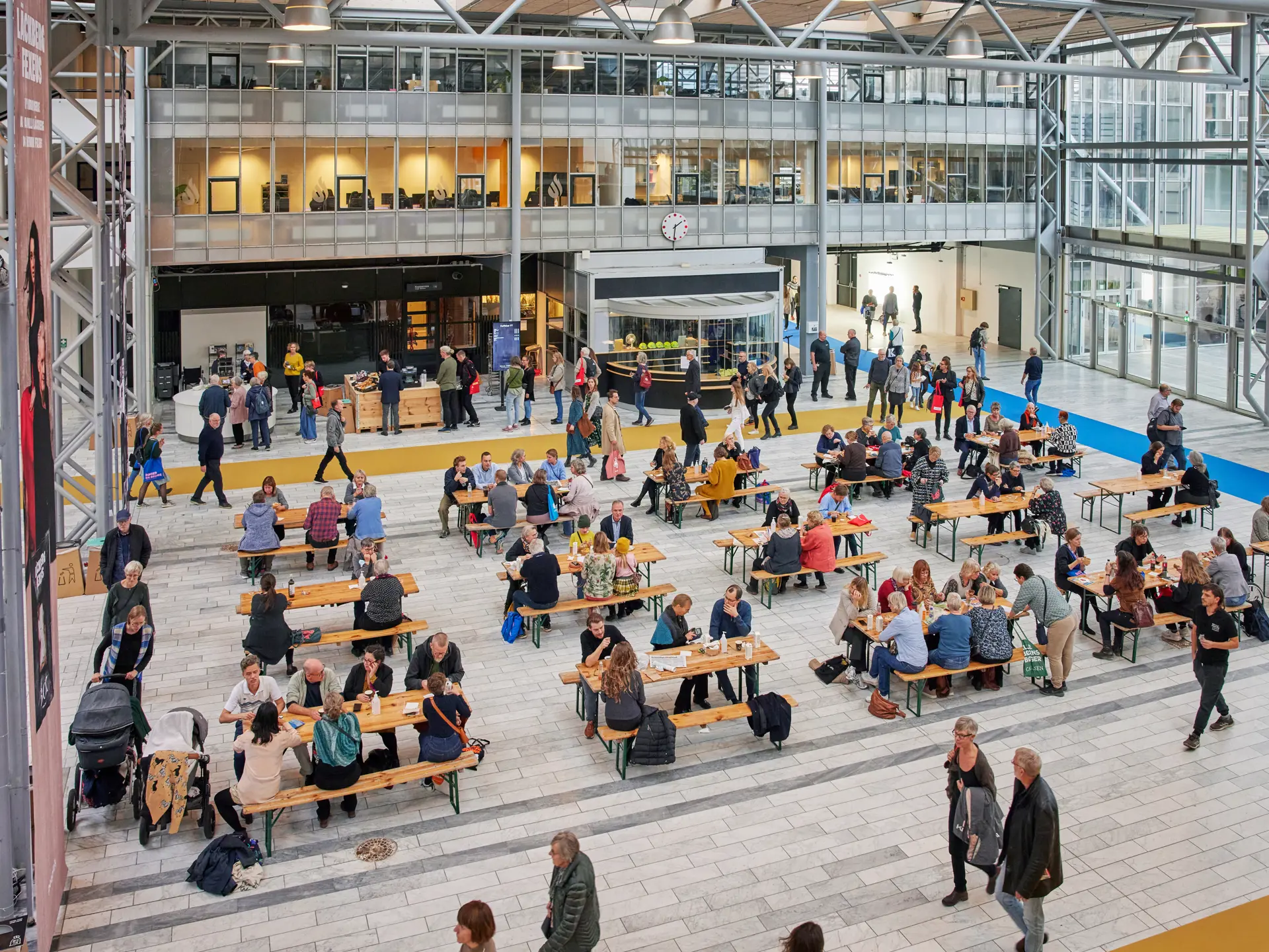 Gæster spiser og netværker ved langborde i Bella Centers foyer.