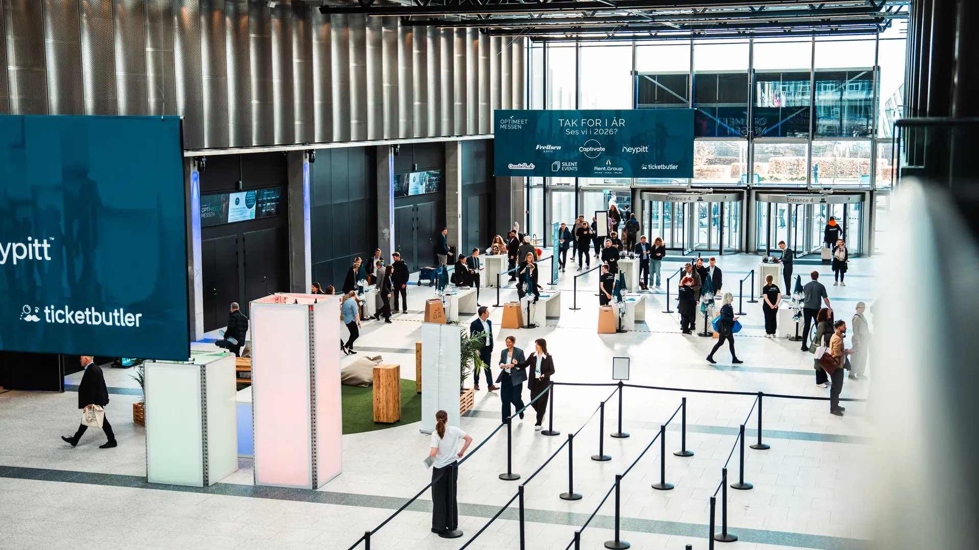 Foyer i Bella Center med gæster ved hovedindgangen under et event.