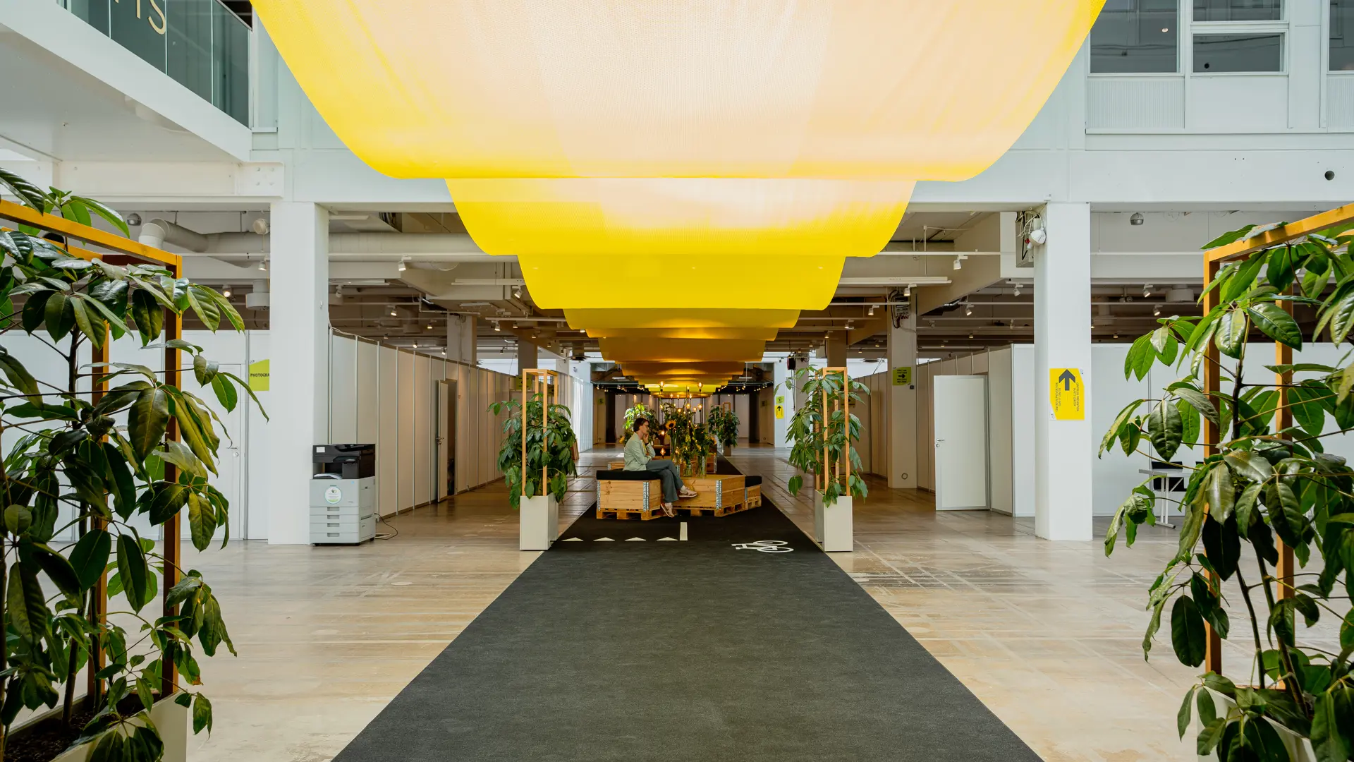 Loungeområde i Hal B i Bella Center med grønne planter og gul loftsdekoration.