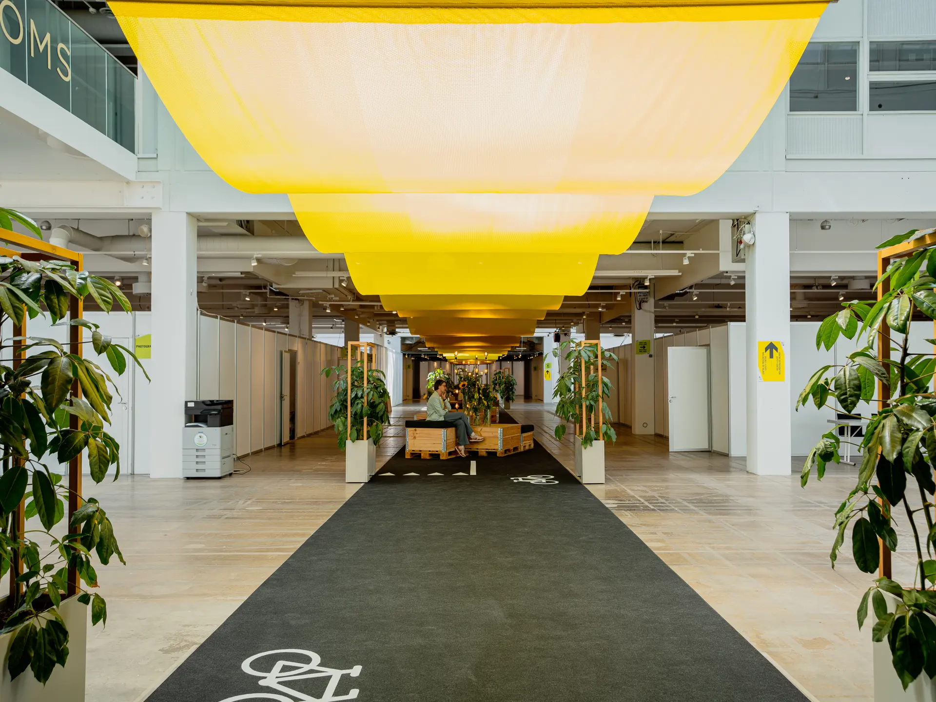 Loungeområde i Hal B i Bella Center med grønne planter og gul loftsdekoration.