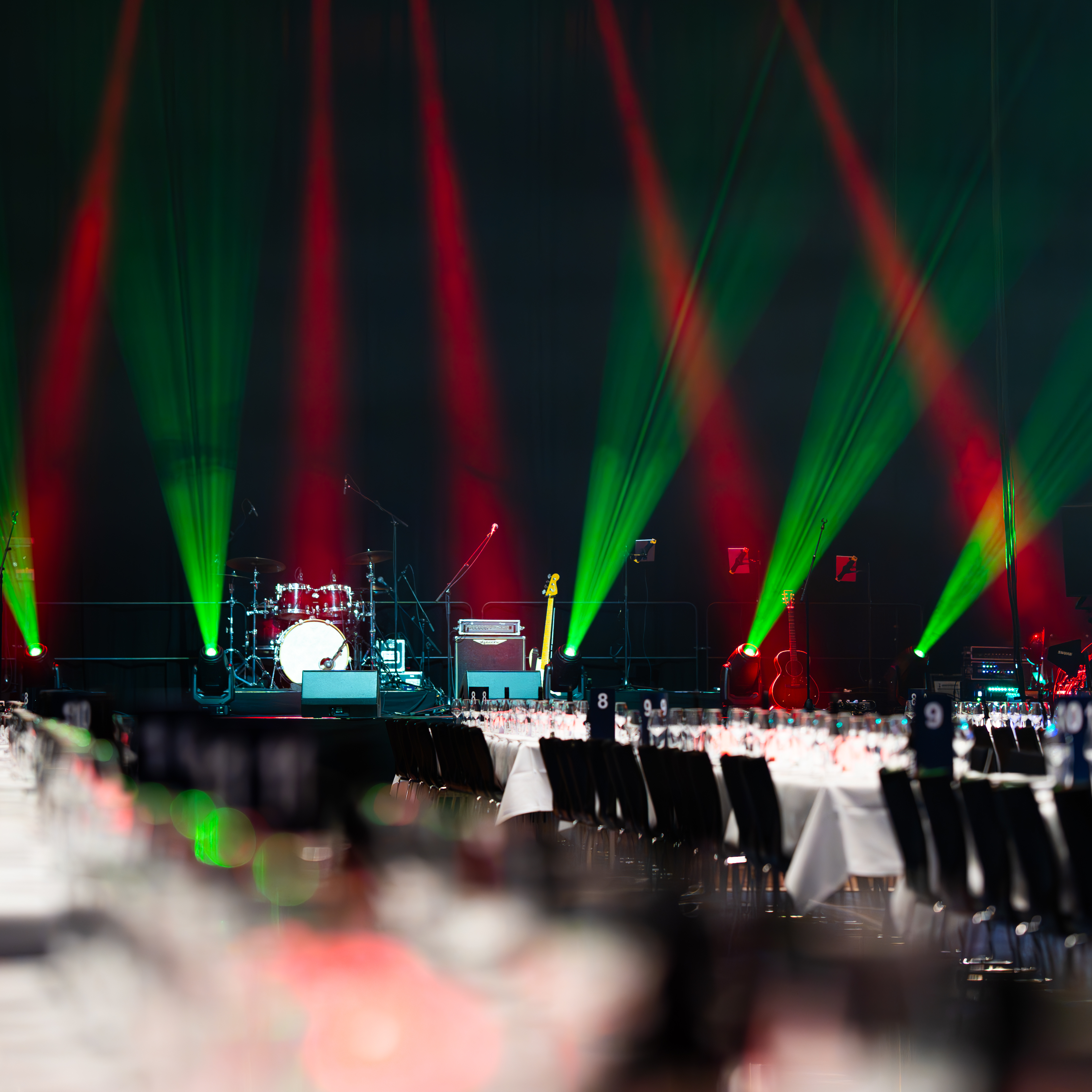 Festlokale med scene, trommesæt, guitar og lys i rød-grønne farver til julefrokost i Bella Center.