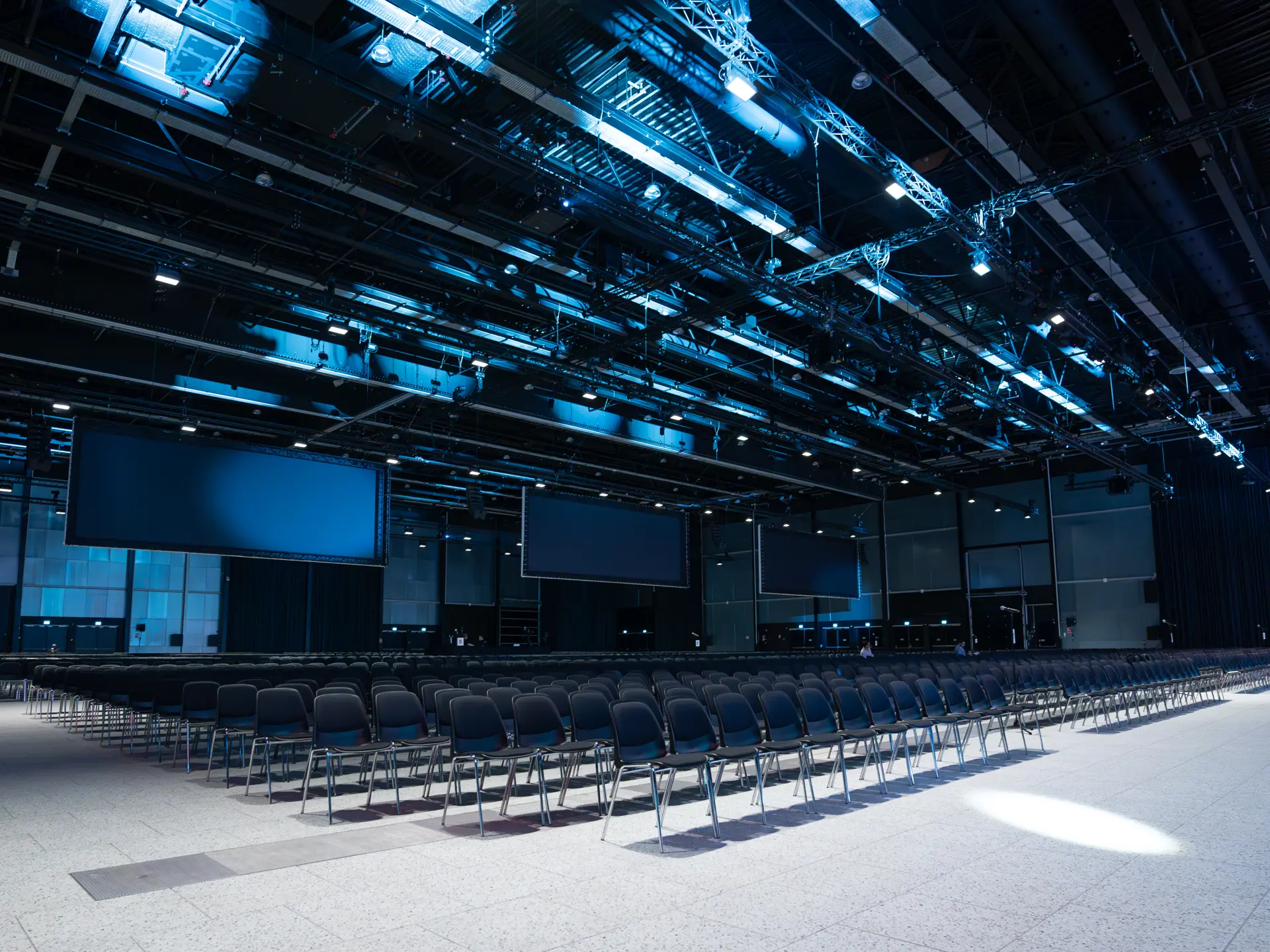 Hal D i Bella Arena indrettet til konference med storskærme og scenelys.