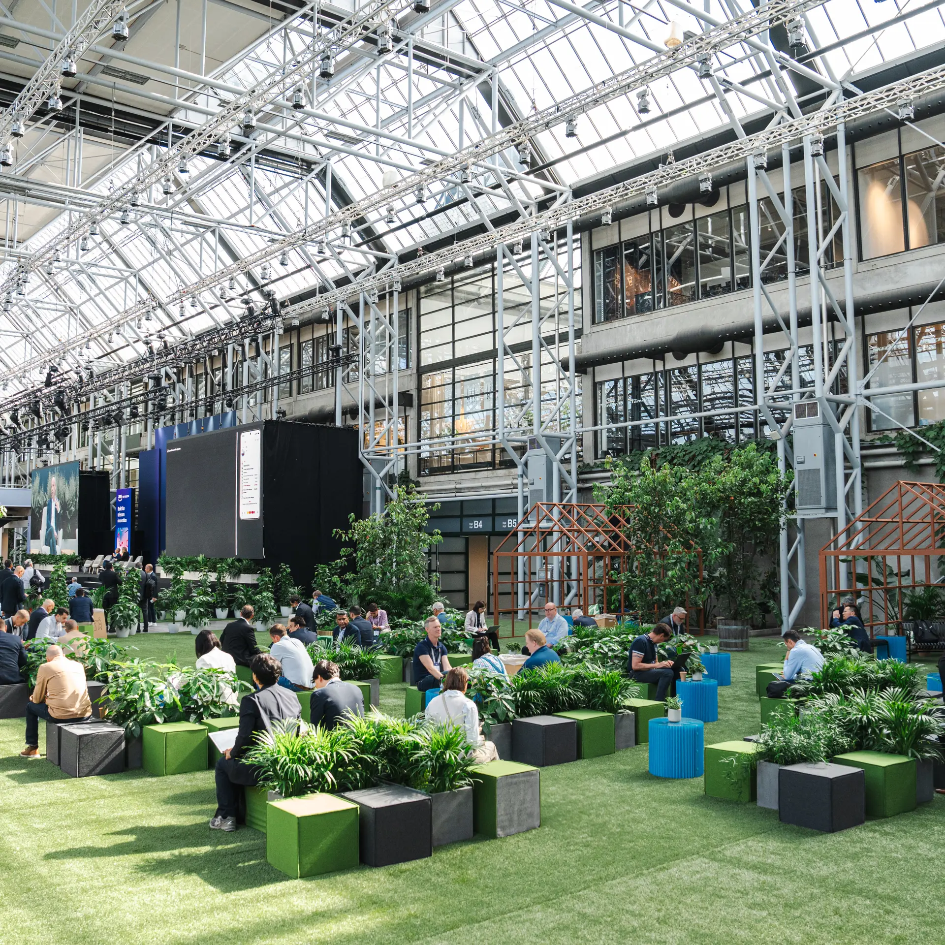 Eventområde med grønne loungezoner og gæster i Bella Center Copenhagen.