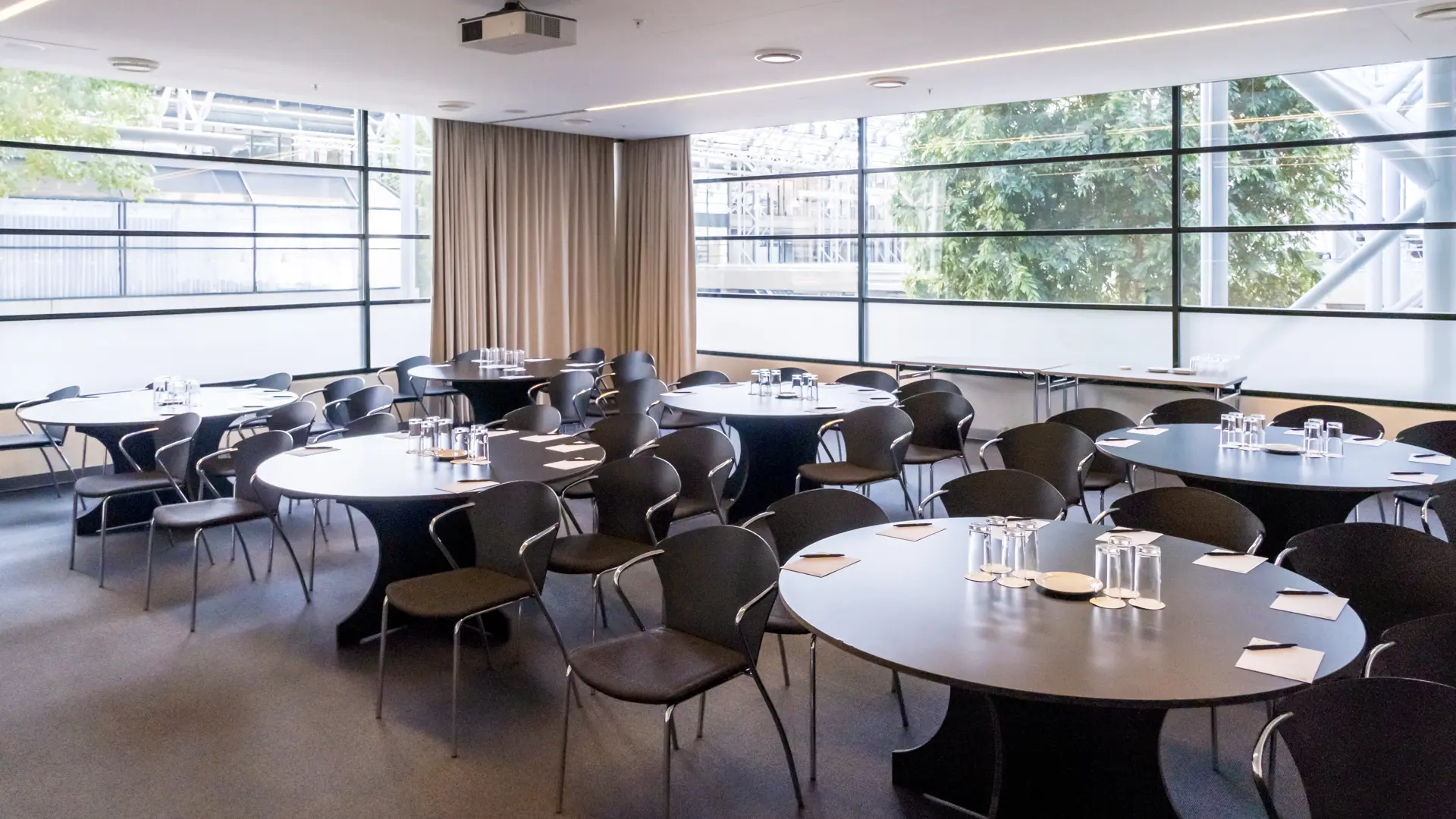 Mødelokale med runde borde og AV-udstyr i Bella Center, København – ideelt til workshops og breakout-sessions.