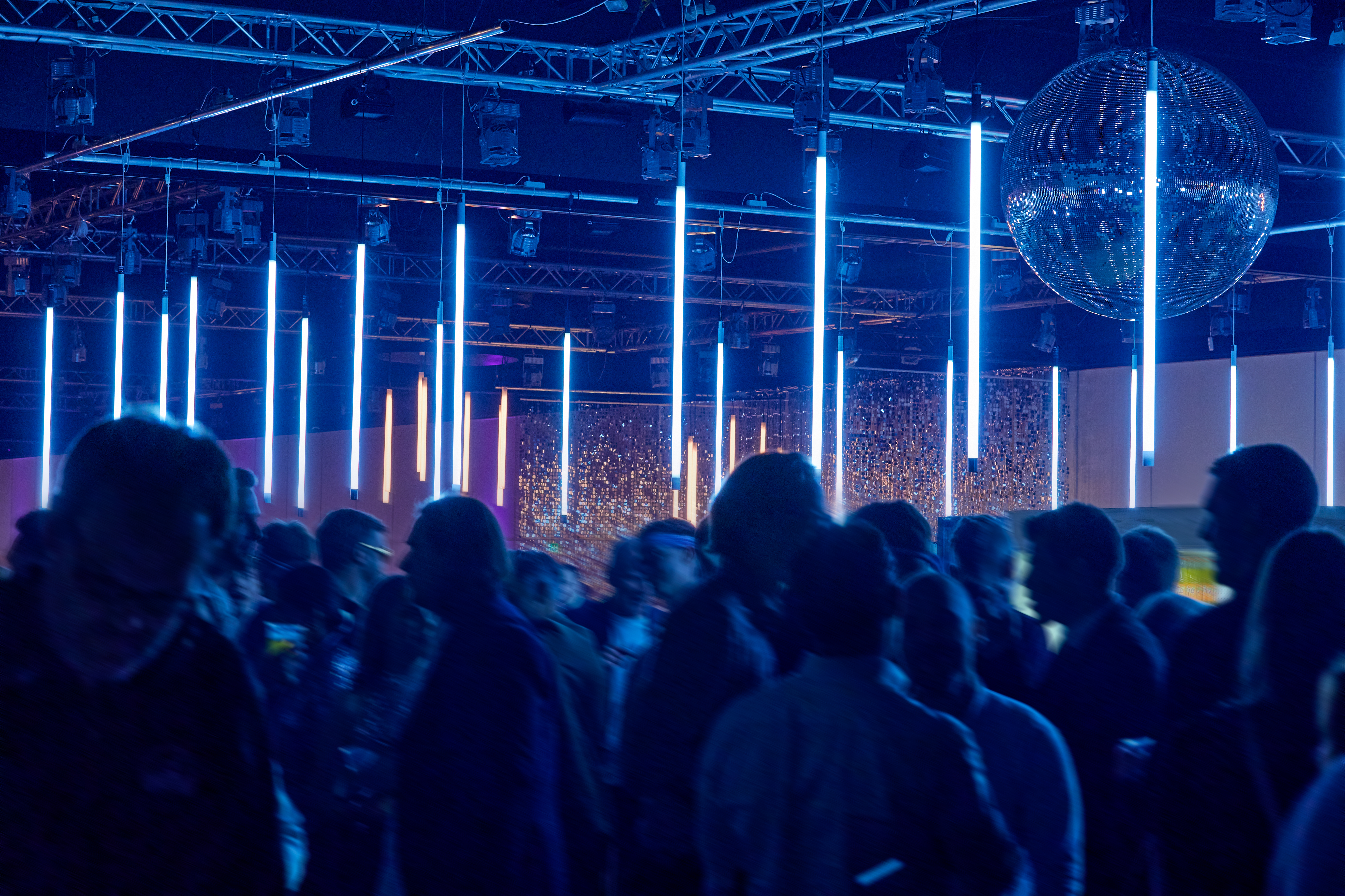 Dansende gæster under blå lysinstallationer og diskokugle til julefrokost i Bella Center.